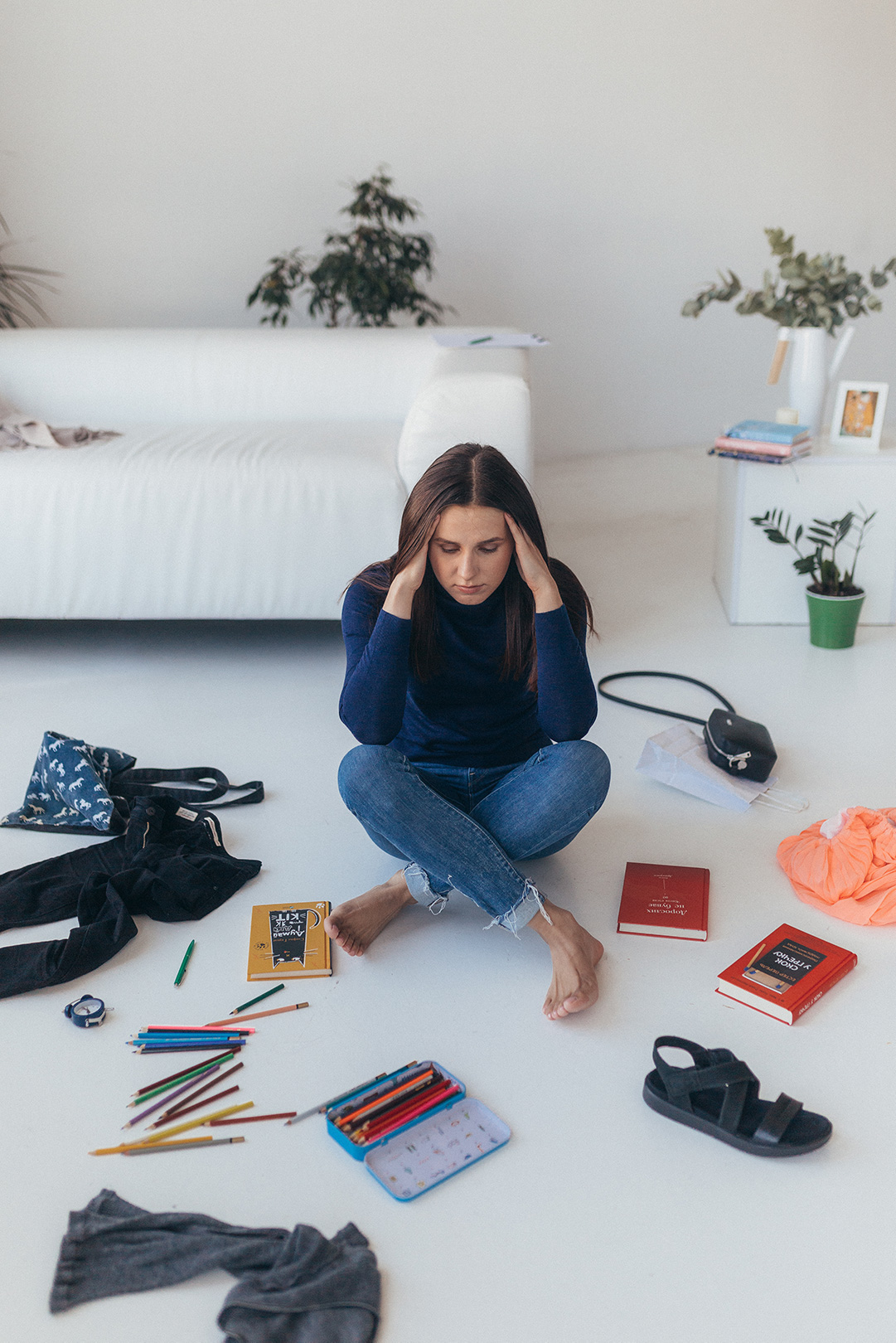 A girl, grabbing her head, sits amidst the chaos